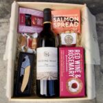 Wine box featuring wine, crackers, chocolate, nuts and salmon