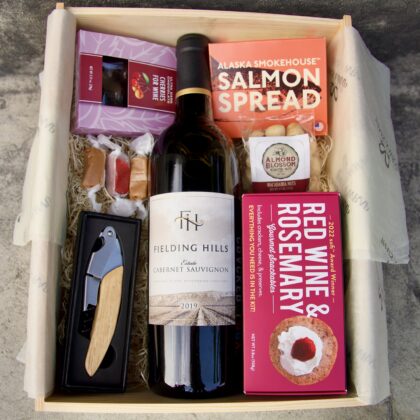 Wine box featuring wine, crackers, chocolate, nuts and salmon